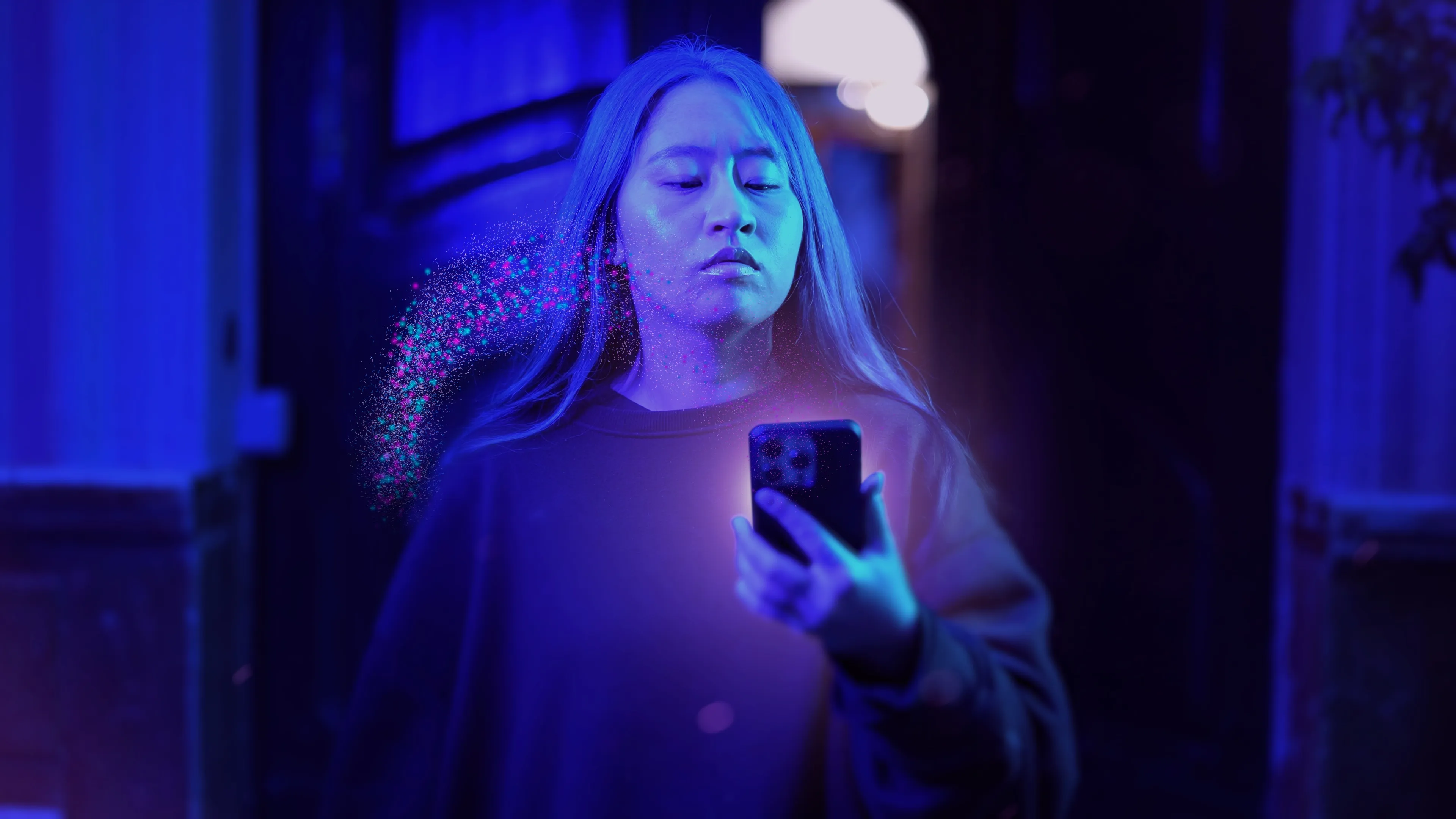 Imagen promocional de «Ídolos. Miradas milenarias»: una persona mira su móvil bajo una luz azul, con un efecto de partículas que la difumina