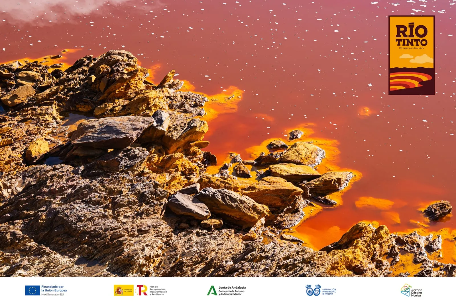 Primer plano de las aguas rojas del Río Tinto corriendo entre rocas ocres, a su paso por Berrocal.