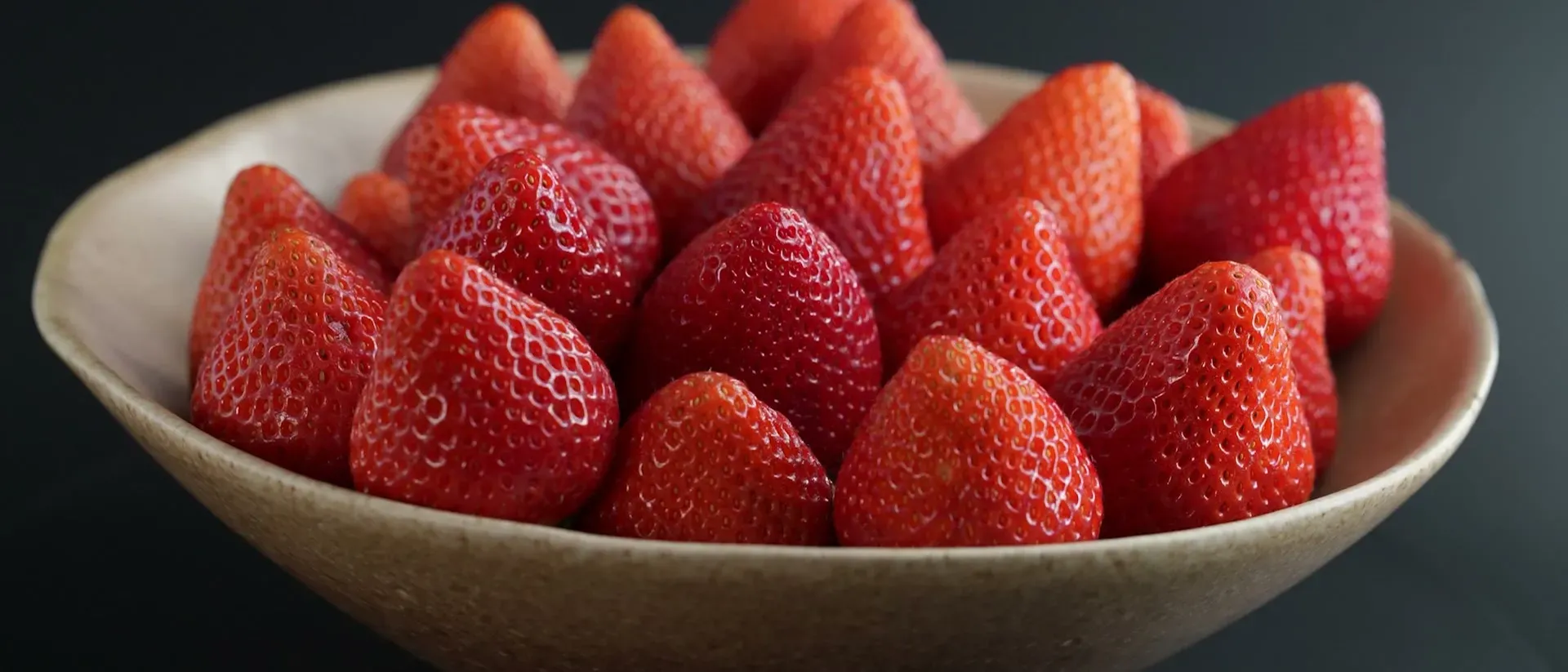 Un cuenco de cerámica lleno de fresas sobre fondo oscuro, en un fotograma de un vídeo de Bis para las redes de Fresón de Palos