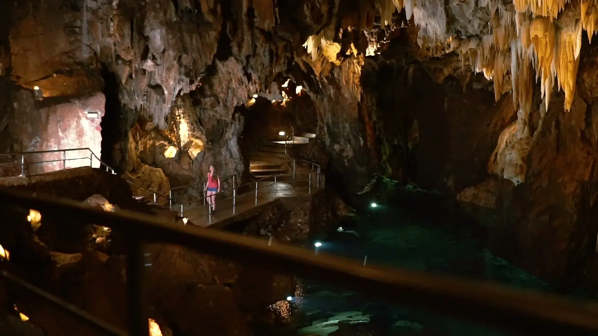 Una visitante recorre la pasarela de la Gruta de las Maravillas, en Aracena, iluminada sobre el lago