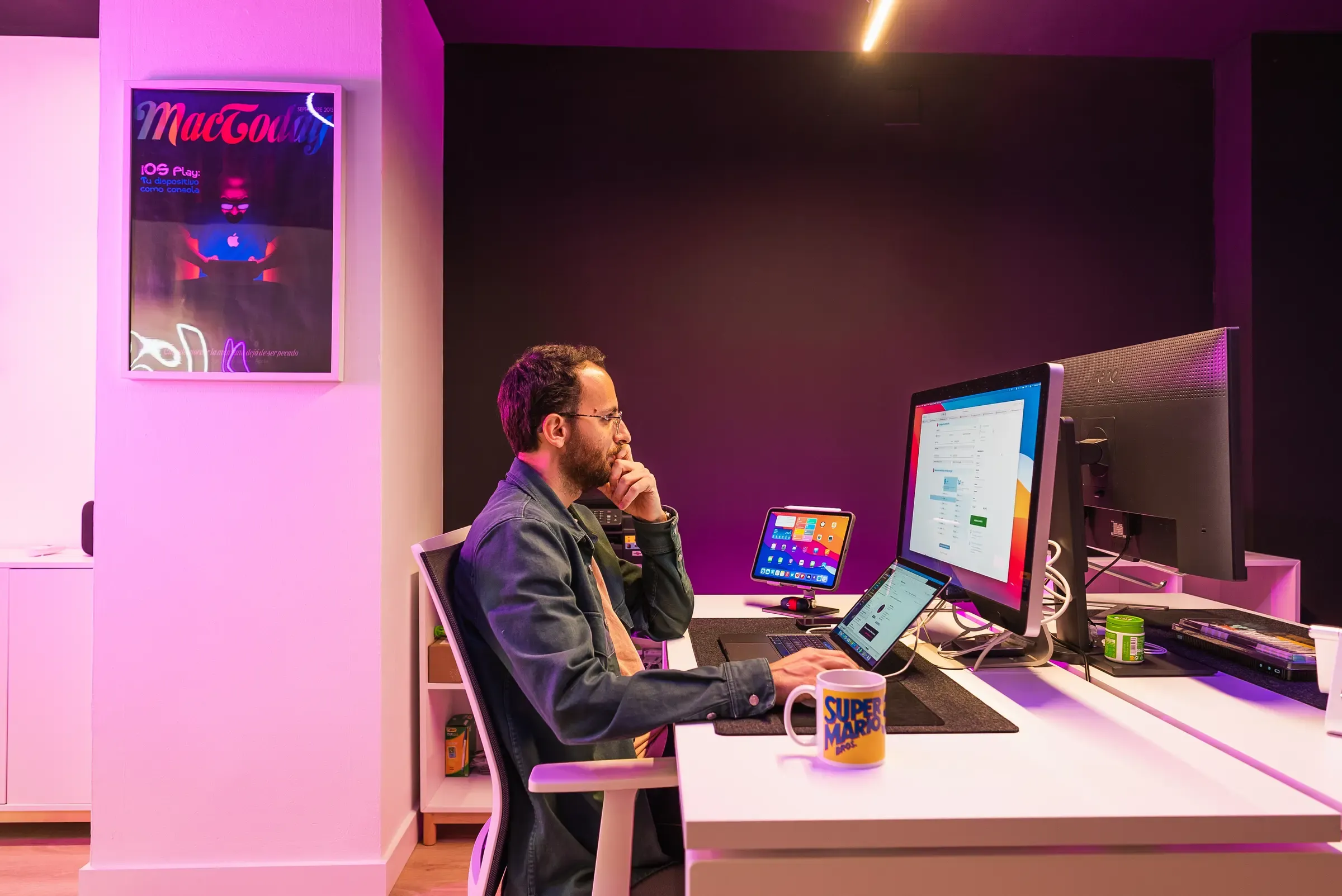 Un miembro del equipo de Bis trabajando frente a sus pantallas en la oficina, bajo la luz violeta del estudio